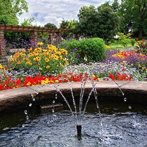 Blick auf einen Springbrunnen und verschiedenfarbig blühende Blumen