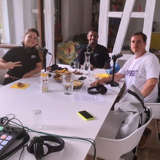 B-Girl Sophie Manuela Lindner, Popping Tänzer Milyon Hagos und Moderator Ingmar Volkmann während der Podcast-Aufnahme. Alle drei sitzen an einem Tisch, jeder hat ein Mikrofon und einen Kopfhörer vor sich.