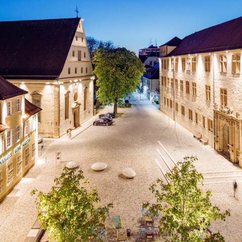 Blick von oben auf den Schlossplatz bei Nacht. Die Gebäuder sind beleuchtet.