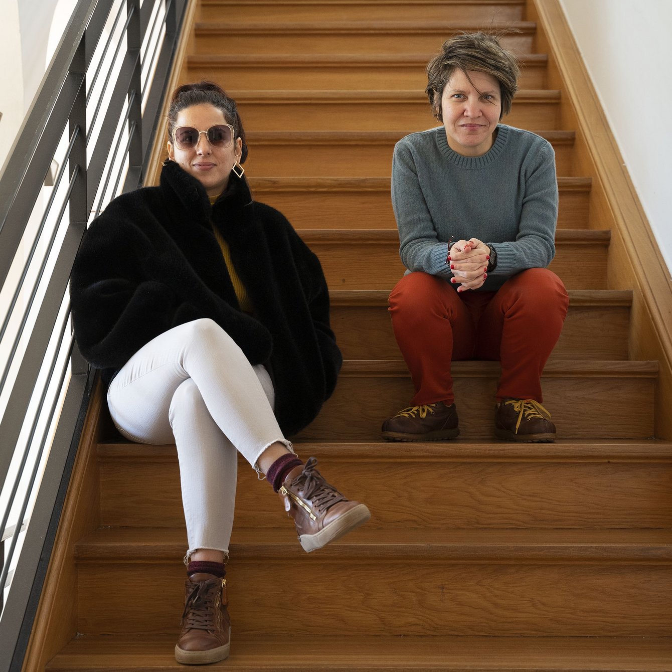 Karina Pino Gallardo und Alessandra Santiesteban sitzen auf einer Holztreppe.