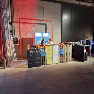 Ein kleiner Verkaufsstand beim "Kunst im Game Symposium" in Stuttgart bietet Getränke an.