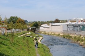 Foto: Blick auf die terassenförmig angelegten Sitz- und Liegemöglichkeiten an der Fils. Auf der anderen Seite der Fils sind Hallen wie von einer Fabrik zu sehen.