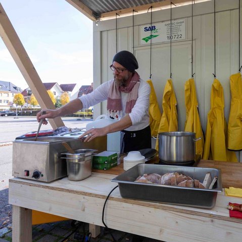 Bild von Marcus Bergmann beim Zubereiten von verschiedenen Speisen in einer improvisierten Küche im Freien.