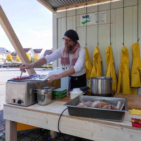 Bild von Marcus Bergmann beim Zubereiten von verschiedenen Speisen in einer improvisierten Küche im Freien.