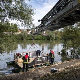 Die Feuerwehr hebt das Festival-Floß mit einer Drehleiter aus dem Neckar.