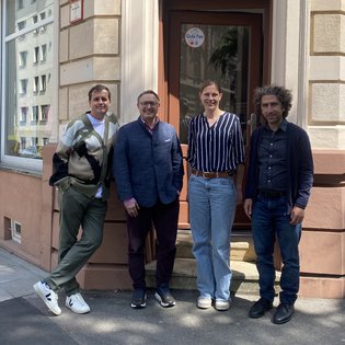 Gruppe vor dem Eingang der Geschäftsstelle der KulturRegion Stuttgart: von links nach rechts: Podcast-Moderator Ingmar Volkmann, Michael Rubinstein, Gemeindedirektor der Israelitischen Religionsgemeinschaft Württembergs, Bettina Pau, Geschäftsführerin der KulturRegion, Dr. Robert Ogman, Projektleiter. Alle Personen lächeln freundlich in die Kamera.