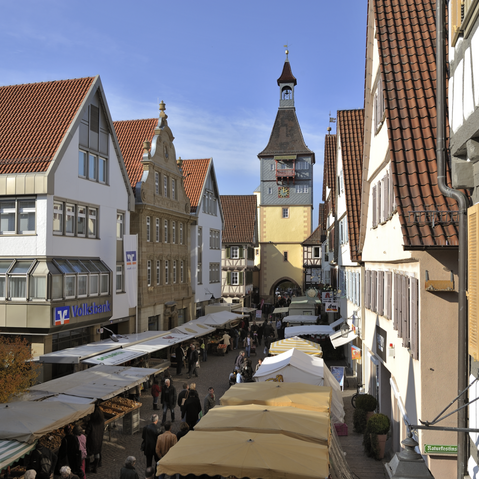 Blick auf den Torturm durch eine Einkaufsstraße mit Marktständen rechts und links.