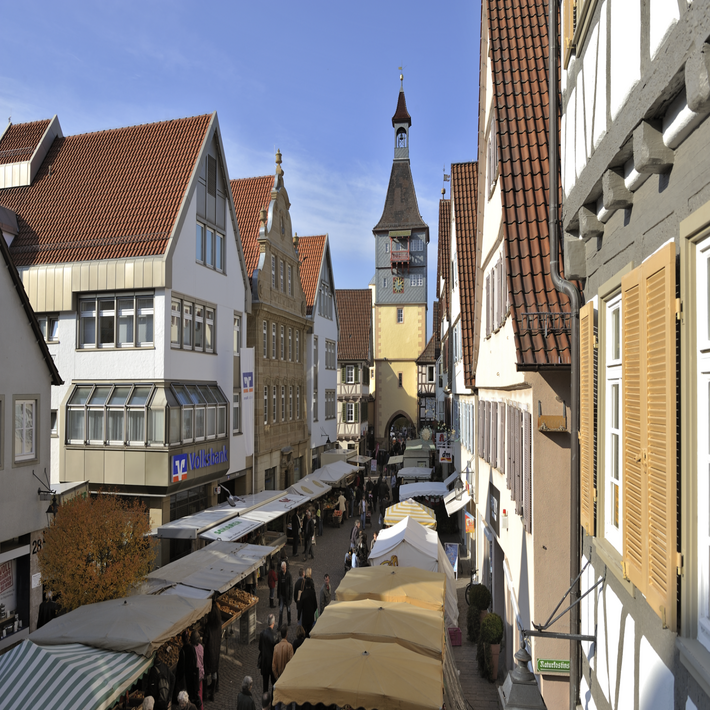 Blick auf den Torturm durch eine Einkaufsstraße mit Marktständen rechts und links.
