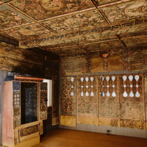 Prunkvoll bemalter Synagogeninnenraum mit farbenfrohen floralen Decken- und Wandmalereien, hebräischen Inschriften und einer geöffneten Toranische. Der Raum zeigt die kunstvolle Gestaltung jüdischer Sakralarchitektur aus vergangenen Jahrhunderten.