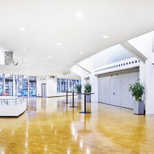 Innenansicht auf das Foyer. Die Wände sind in hellen Tönen gehalten, das Foyer verfügt über einen Parkettboden.