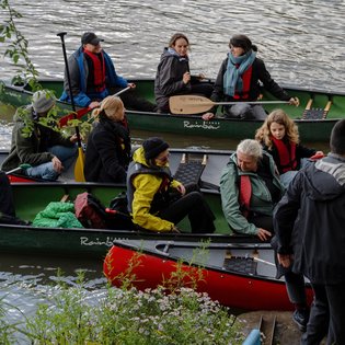 Mehrere mit Personen besetzte Kanus an einer Anlegestelle.