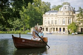 Blick über den See auf Monrepos. Ein Paar fährt Boot auf dem See.