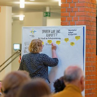 eine Frau zeichnet auf eine Pinnwand die Diskussion mit
