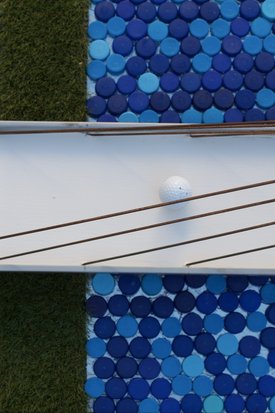 Minigolfbahn mit weißen Spielflächen, blauen runden Fliesenmustern und einem weißen Golfball