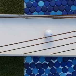 Minigolfbahn mit weißen Spielflächen, blauen runden Fliesenmustern und einem weißen Golfball