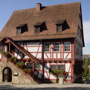 Zweigeschossiges Fachwerkhaus mit rotem Ziegeldach, Außentreppe und Blumenkästen, dient als Museum.