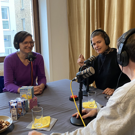 Gäst*innen Sara Dahme und Katja Kranich und Moderator Ingmar Volkmann während der Aufnahme des Podcast. Alle drei sitzen an einem Tisch, tragen Kopfhörer und haben Tischmikrofone vor sich stehen.