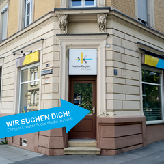 Bild des Eingangsbereichs der Geschäftsstelle der KulturRegion Stuttgart. Auf das Bild ist ein blauer Pfeil mit dem Text: » Wir suchen Dich! Content Creator für Instagram, Facebook & TikTok (m/w/d)« gelegt.