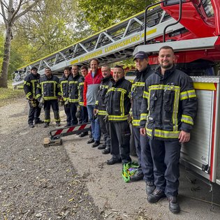 OB und Vorsitzender der KulturRegion Dr. Matthias Knecht mit den Mitarbeitenden der Feuerwehr vor einem Drehleiterfahrzeug.