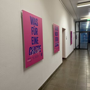 Plakate der Ausstellung »Schlamassel Tov« sind in einem Gang des Stuttgarter Rathauses an weißen Wänden aufgehängt.