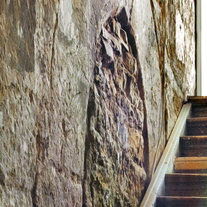 Eine rekonstruierte historische Wand mit einem freigelegten Spitzbogen und einer Treppe daneben.