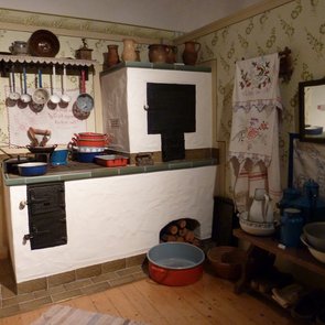 Blick in die Ausstellung: es ist eine alte Kücheneinrichtung mit einem Holzherd und einem Holzbackofen zu sehen