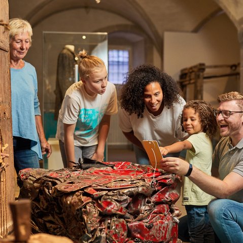 Blick in die Ausstellung. Eine Familie betrachtet ein Ausstellungsobjekt