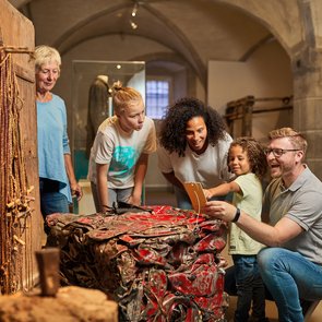 Blick in die Ausstellung. Eine Familie betrachtet ein Ausstellungsobjekt