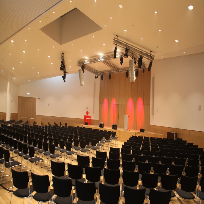 Innenansicht auf einen bestuhlten Raum und eine Bühne.