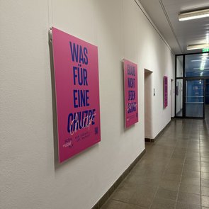 Plakate der Ausstellung »Schlamassel Tov« sind in einem Gang des Stuttgarter Rathauses an weißen Wänden aufgehängt.