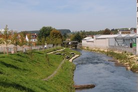 Foto: Blick auf die terassenförmig angelegten Sitz- und Liegemöglichkeiten an der Fils. Auf der anderen Seite der Fils ist ein großes Gebaüde zu sehen.