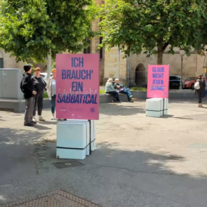 Foto der Schlamassel Tov Ausstellung in Esslingen auf dem Marktplatz. Im Vordergrund ist ein Plakat mit der Aufschrift »Ich brauch' ein Sabbatical« zu sehen.