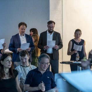 Personen aus dem Publikum beim Singen von einem Blatt.