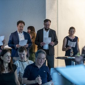Personen aus dem Publikum beim Singen von einem Blatt.