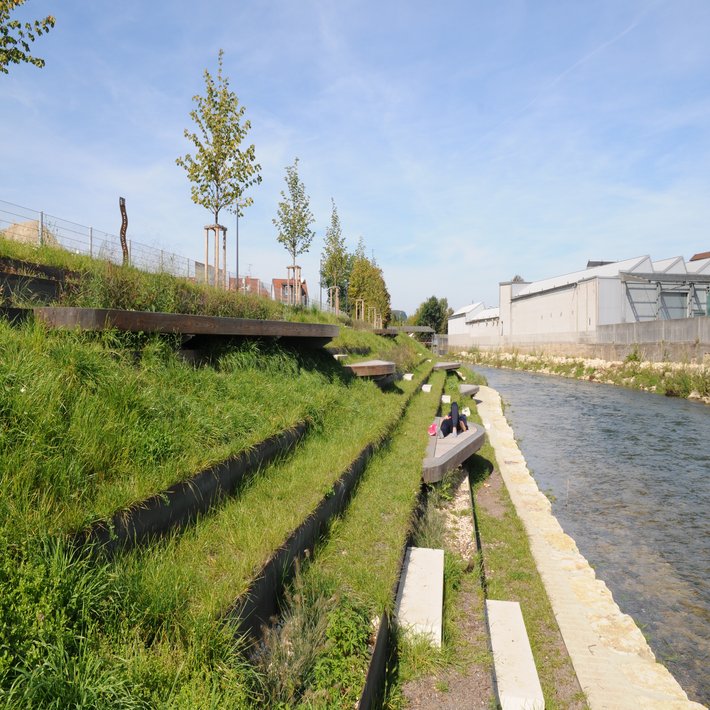 Foto: Blick auf die terassenförmig angelegten Sitz- und Liegemöglichkeiten an der Fils. Eine Person geniesst liegend den Sonnenschein.