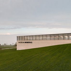 Blick über eine Wiese auf das sehr morderne Gebäudes des Museums