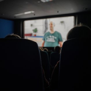 Blick durch zwei Kinosessel hindurch auf die Leinwand, auf der einer der Kurzfilme läuft.