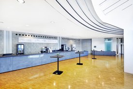 Innenansicht auf das Foyer. Die Wände sind in hellen Tönen gehalten, der Bereich verfügt über einen Parkettboden. 