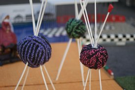 Nahaufnahme von bunten, gestrickten Kugeln, die an weißen Stäben befestigt sind
