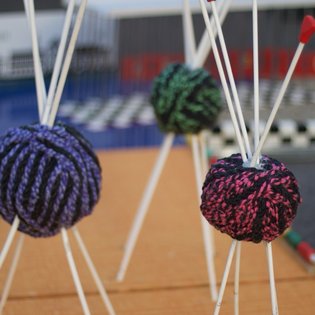Nahaufnahme von bunten, gestrickten Kugeln, die an weißen Stäben befestigt sind