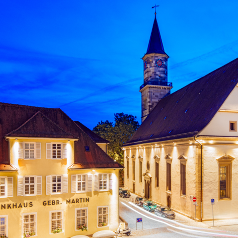 Blick auf die evangelische Stadtkirche bei Nacht. Alle Gebäude sind beleuchtet.