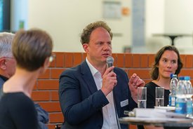 Dr. Matthias Knecht spricht auf dem Podium ins Mikrofon und gestikuliert mit der Hand
