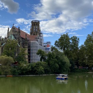 Das Festival-Floß auf dem Feuersee in Stuttgart-West. Im Hintergrund ist die eingerüstete Johanneskirche zu sehen.