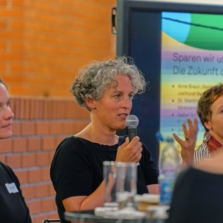 Dr. Birte Werner spricht ins Mikrofon und gestikuliert mit offener Hand