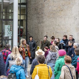 Die Gruppe der Teilnehmer*innen vor dem Eingang des Bauernkriegsmuseums in Böblingen. In der Mitte der Gruppe steht Kunstvermittlerin Sara Dahme und spricht zur Gruppe.