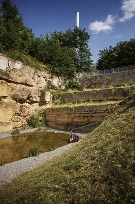 Ein kleines Kind schaut auf einen kleinen See im Travertinpark. Der See ist von Gesteinskanten des Steinbruchs umgeben.