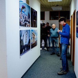 Person in blauer Jacke steht in einem Flur mit an den Wänden hängenden Sportfotografien