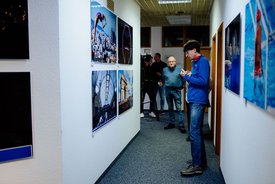 Person in blauer Jacke steht in einem Flur mit an den Wänden hängenden Sportfotografien