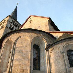 Aussenansicht mit Chor, Apsiden und Turm vor blauem Himmel