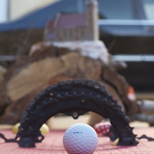 Golfball vor einem halbkreisförmigen Hindernis auf einem roten Untergrund